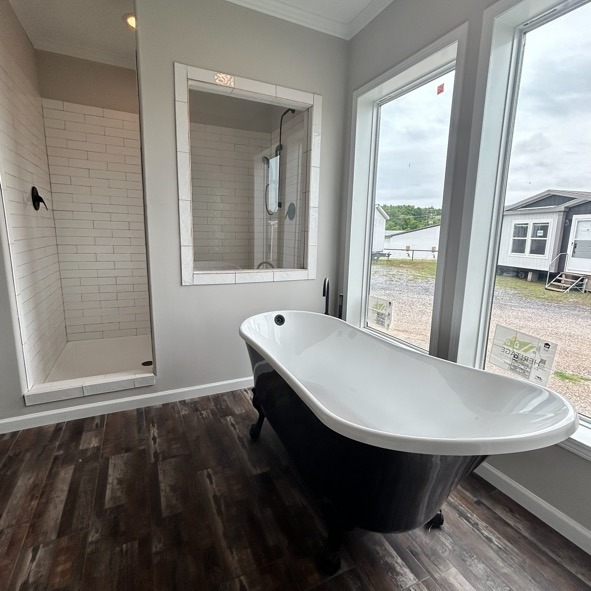 A modern bathroom with a freestanding black and white clawfoot tub, a glass-enclosed shower, and large windows offering a view outside.