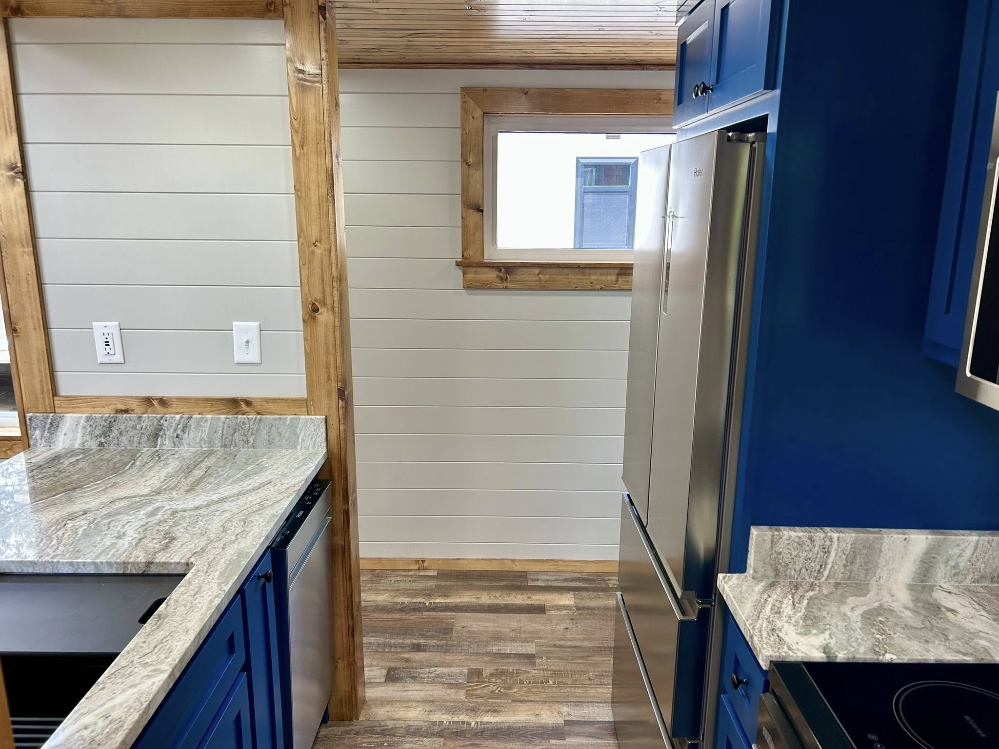 Bright kitchen interior with blue cabinets, stainless steel appliances, and grey marble countertops. The space feels modern and inviting.
