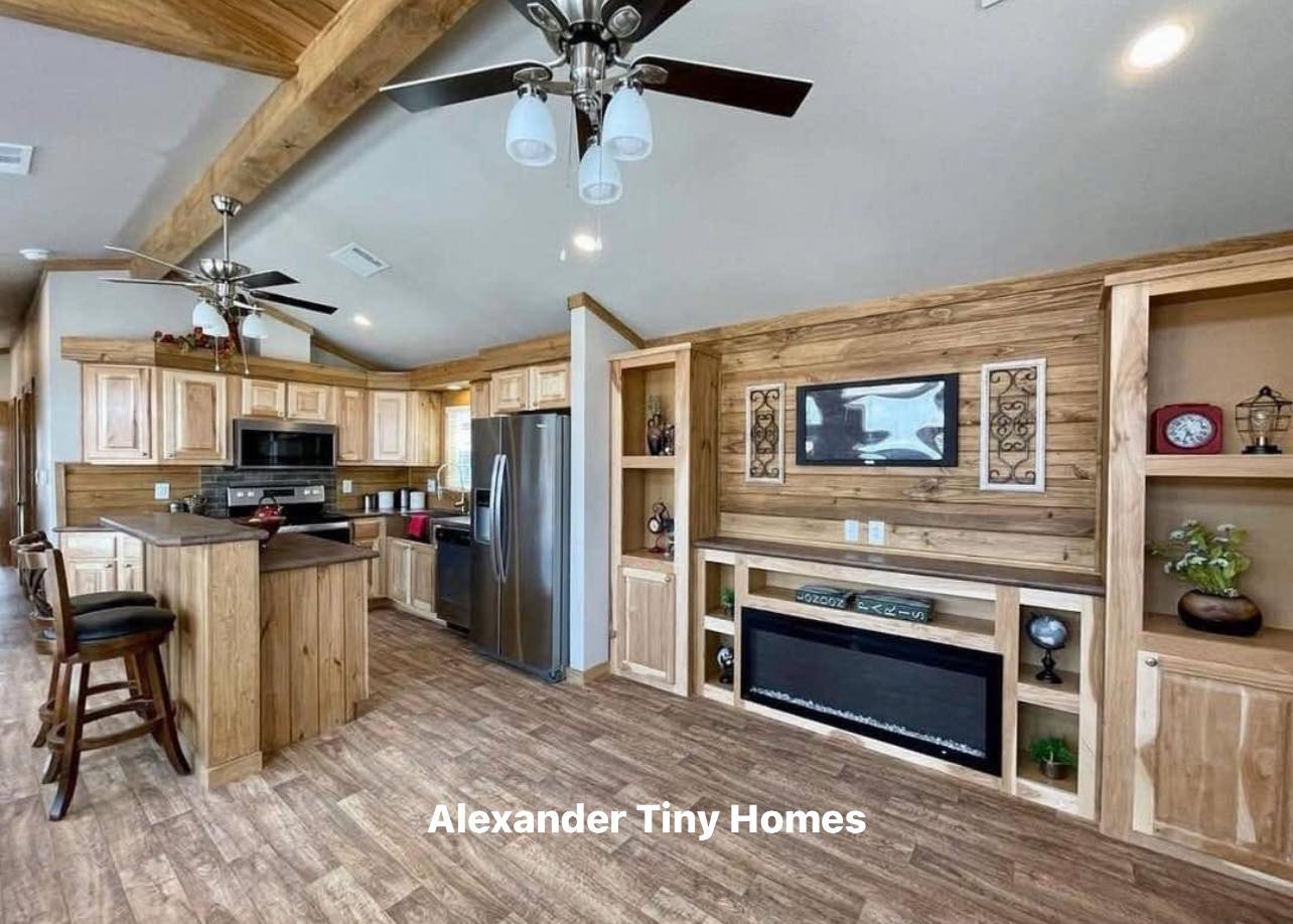 Rustic kitchen in a tiny home featuring wooden cabinets, stainless steel appliances, ceiling fans, and built-in shelves with decor. Warm and cozy atmosphere.