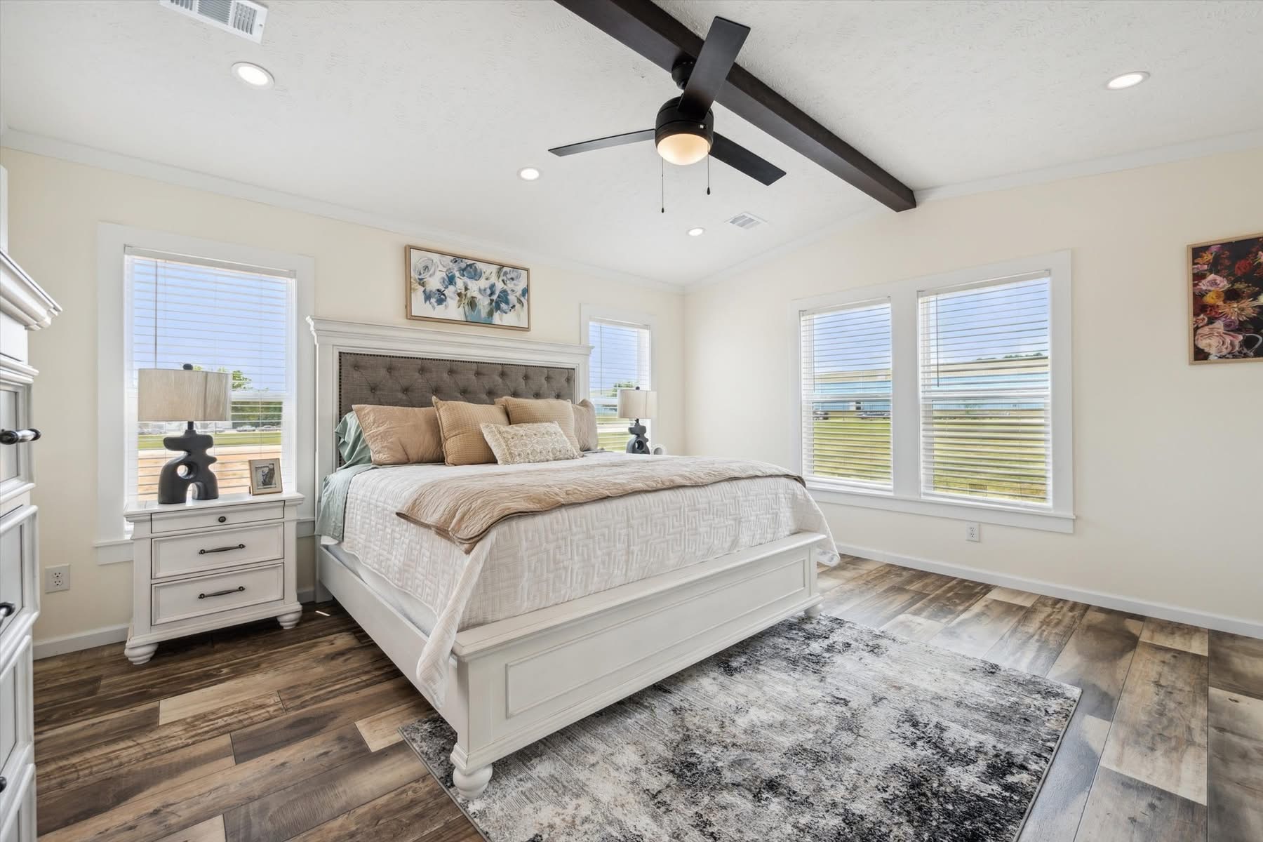 Bright hallway with white walls and rustic wood flooring. Large windows on the right offer ample natural light. Doors on the left lead to other rooms.