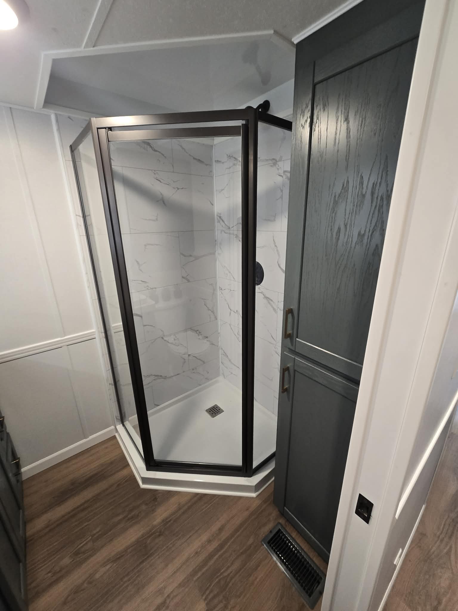View of a spacious, beige carpeted room through black vertical bars, with wooden ceiling panels and large windows, conveying an open, airy feel.