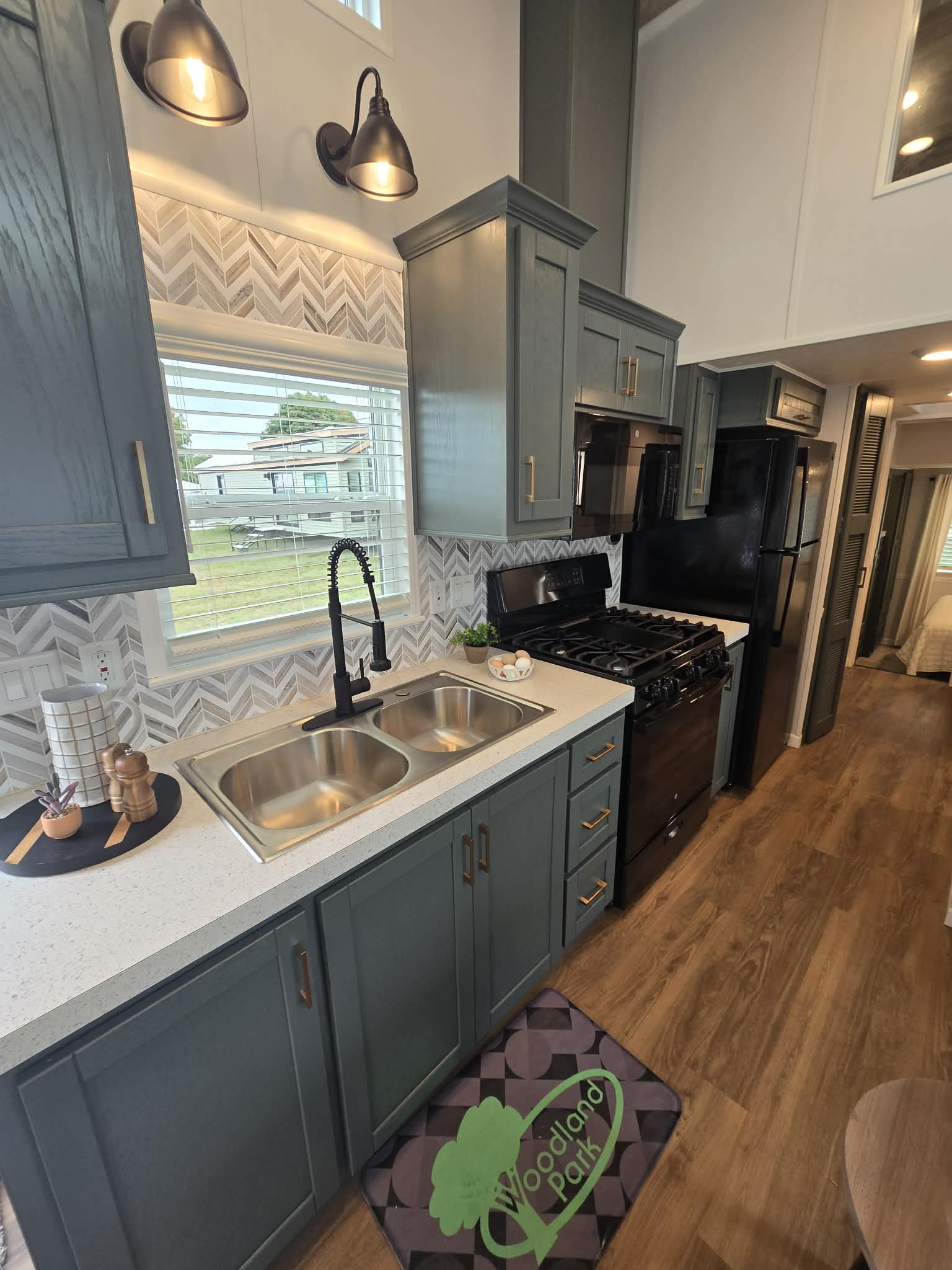 Modern kitchen with dark gray cabinets, stainless steel appliances, and a dual sink. Geometric backsplash adds style. Bright and cozy ambiance.