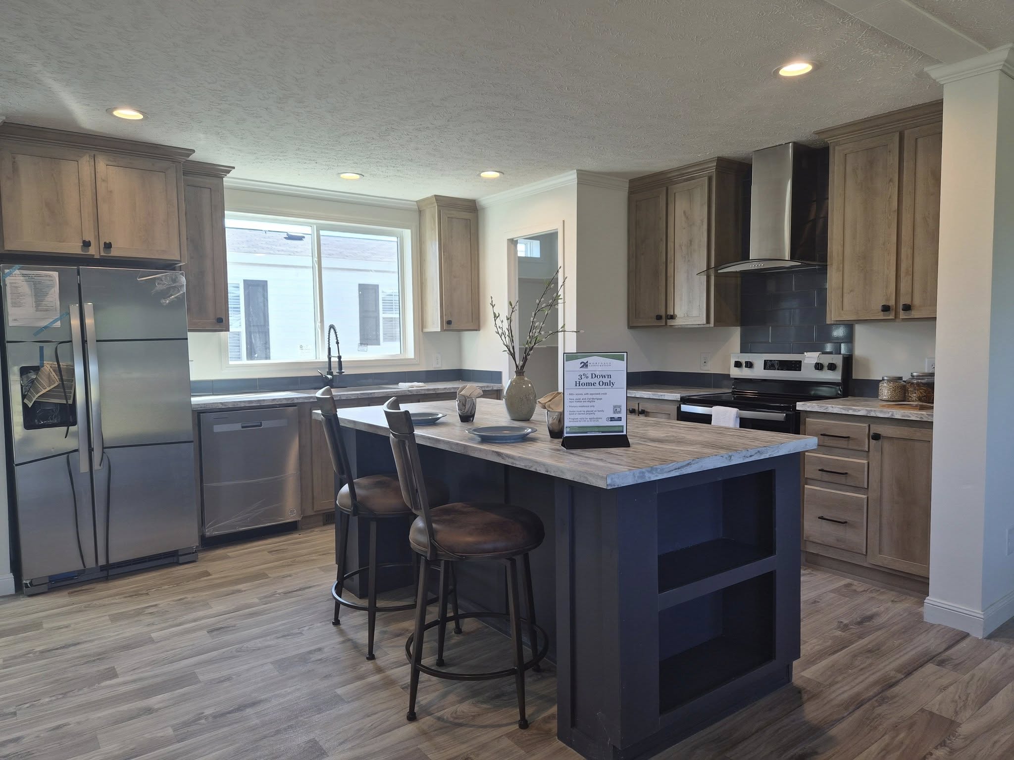 Modern kitchen with wooden cabinets, stainless steel appliances, a large island with two bar stools, and decorative vases. Bright, clean, and inviting.