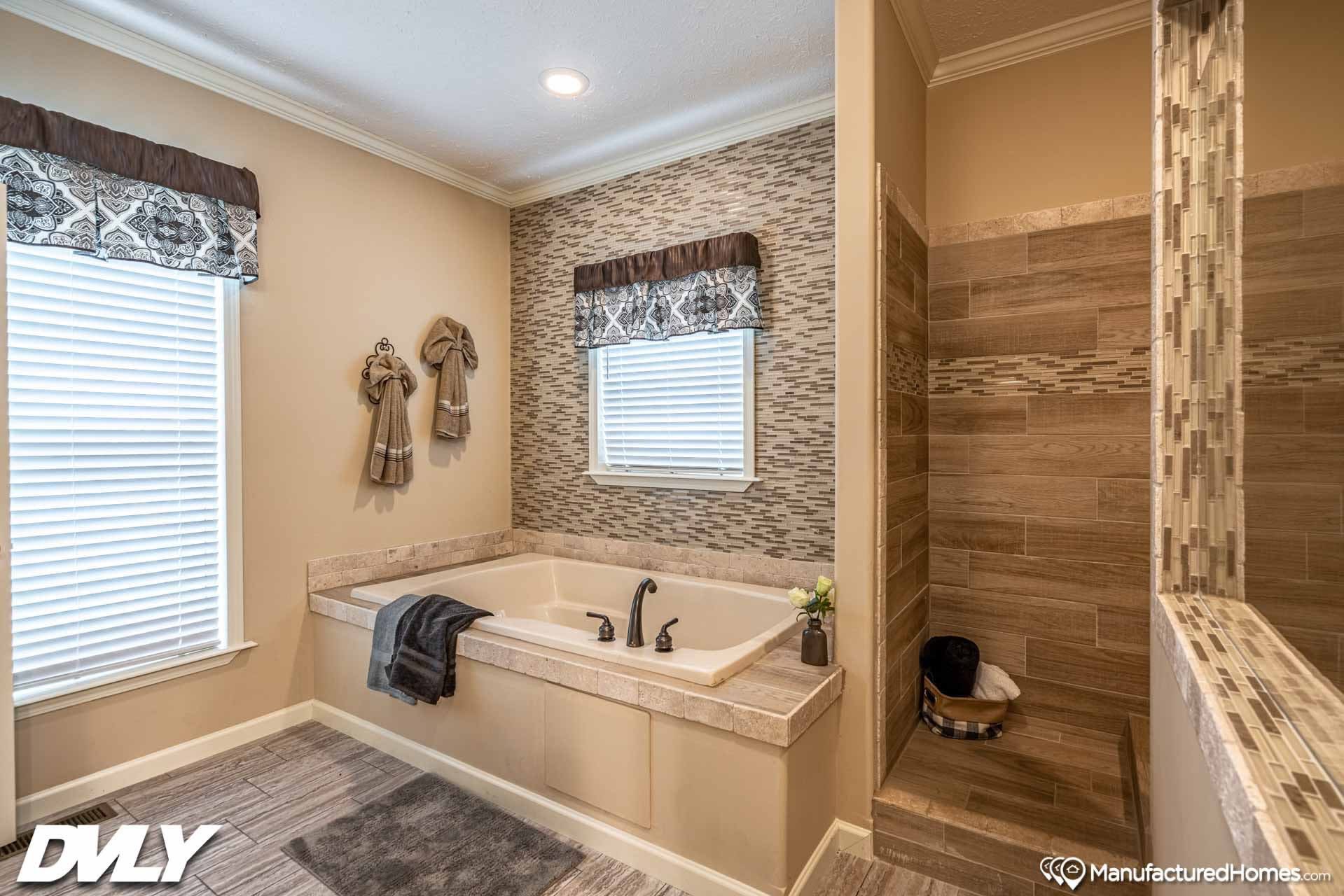 Luxurious bathroom with a built-in tub, modern bronze fixtures, and a tiled walk-in shower. Warm beige tones create a relaxing, elegant ambiance.