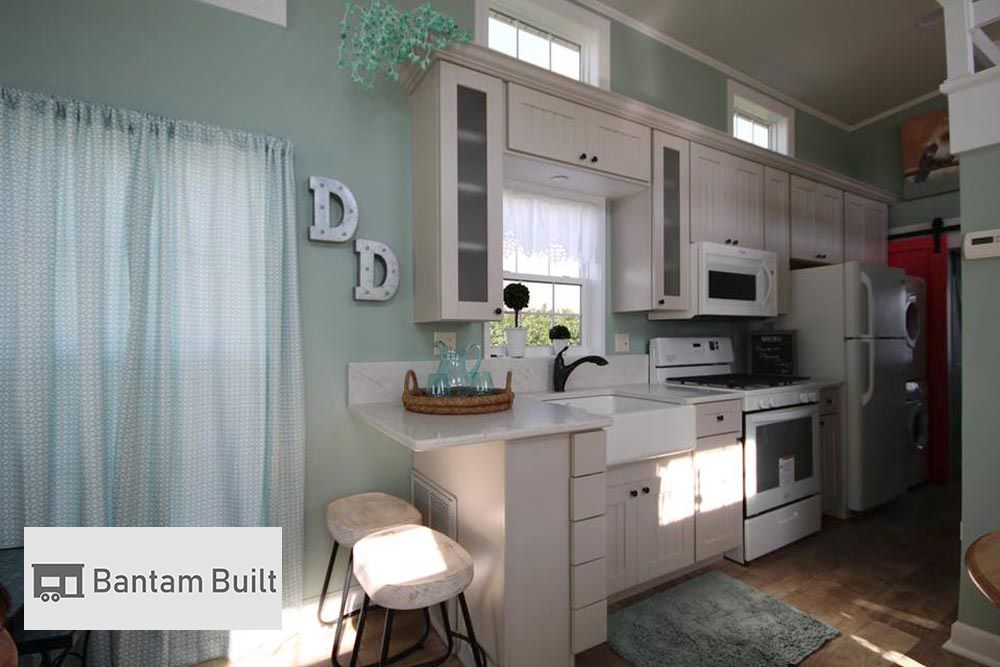 Cozy kitchen with mint green walls, white cabinets, and modern appliances. Soft light filters through a window above the sink, creating a warm, inviting atmosphere.