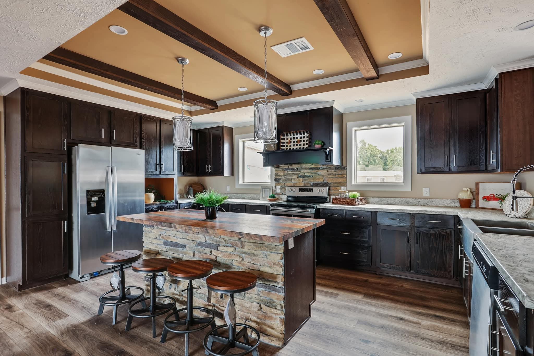 Modern kitchen with dark wood cabinets, stone island, and wooden stools. Features stainless steel appliances, pendant lights, and warm tones. Cozy and elegant.