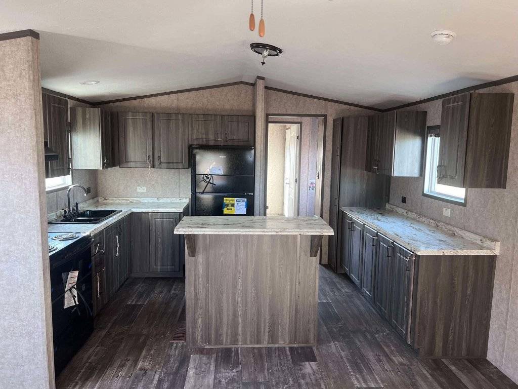 A modern kitchen with gray cabinets, marble countertops, and a central island. It features a black refrigerator and stove, creating a clean, sleek look.