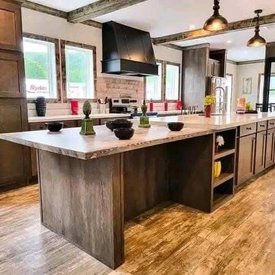 Spacious kitchen with a rustic island, pendant lights, and wooden floors. Features dark wooden cabinets, modern appliances, and elegant decor. Cozy and inviting.