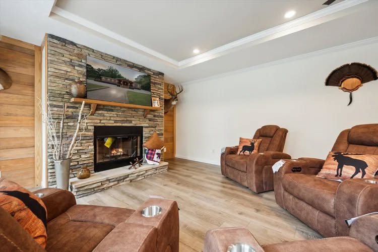 Cozy living room with brown recliners featuring animal pillows, a stone fireplace, and a mounted TV. Rustic decor with a warm, inviting atmosphere.
