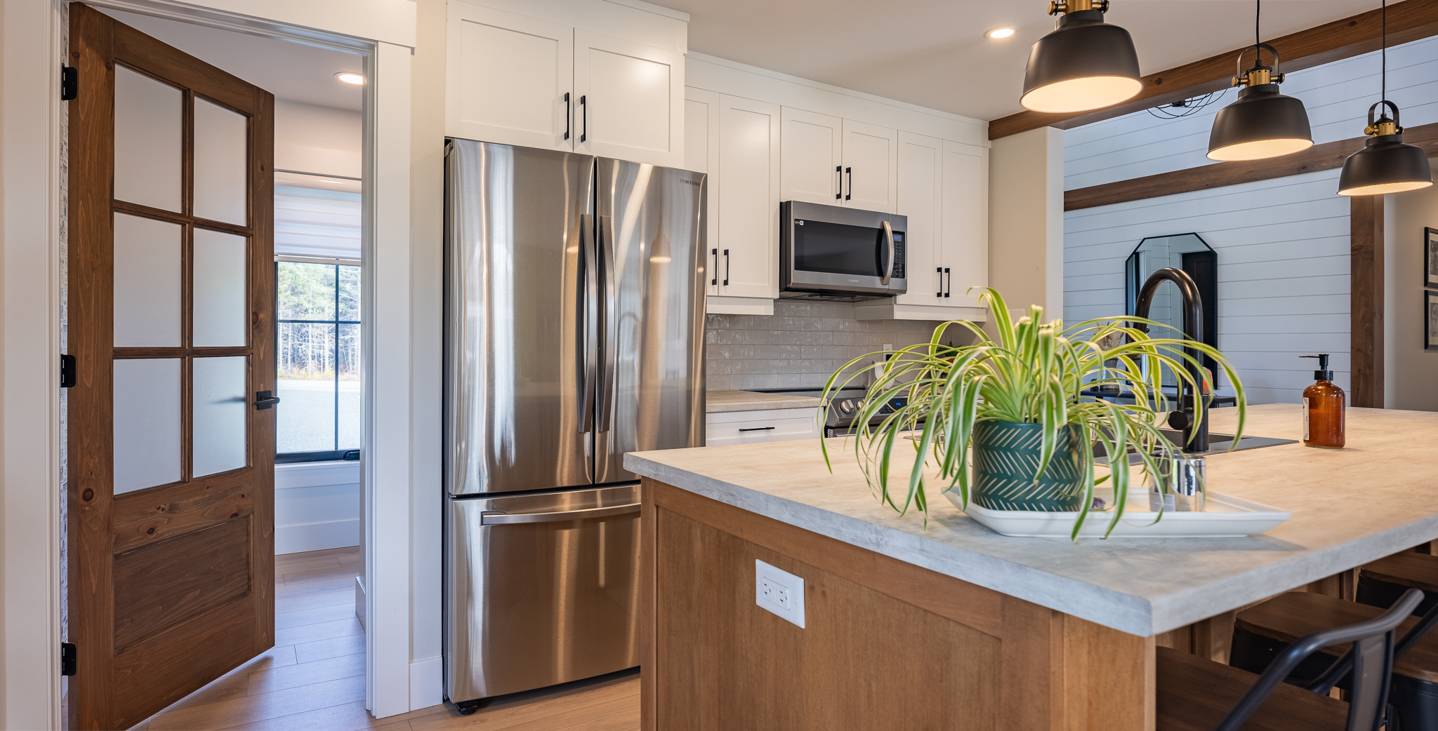 Modern living room with white walls, a mounted TV, built-in shelves, and a cozy fireplace. Features mustard chair, brown sofa, and large window.