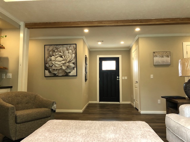 Modern living room with beige walls and a dark wooden floor. A large flower painting and a cushy armchair add warmth. The atmosphere is cozy.