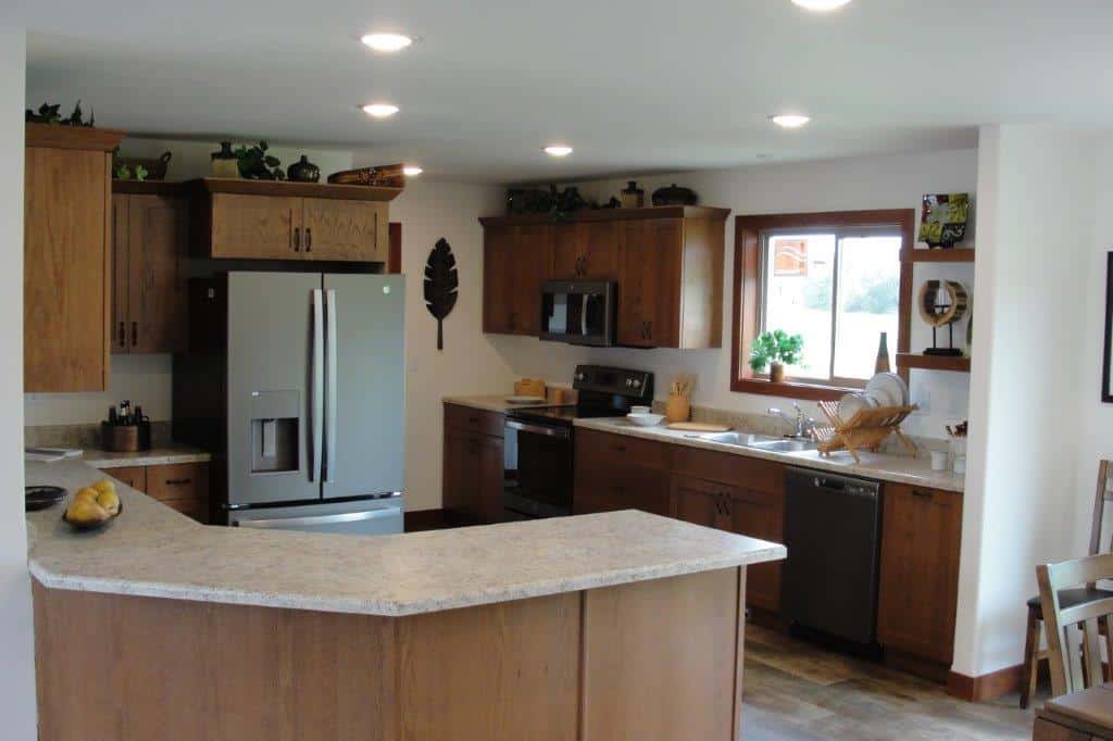 Modern kitchen with a U-shaped layout, featuring wooden cabinets, a stainless steel fridge, and a window above the sink. Warm, inviting atmosphere.