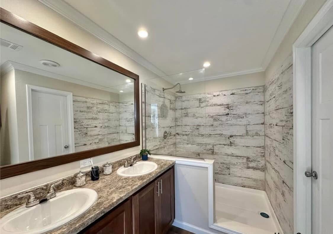 Modern bathroom with double sinks, marble countertop, and large mirror. A glass shower enclosure features rustic white wood panel walls, creating a sleek, fresh look.