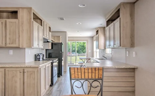 Bright kitchen with light wooden cabinets, an island, modern appliances, and a window showing a lush backyard. Inviting and spacious ambiance.
