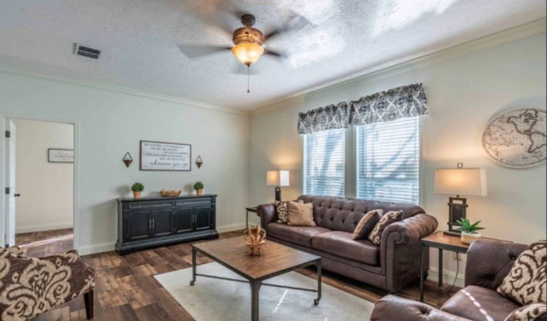 A cozy dining room with a wooden table and four chairs, adorned with a potted plant. The room features a wood-paneled accent wall, a window with blinds, and a chandelier overhead, creating a warm, inviting atmosphere.