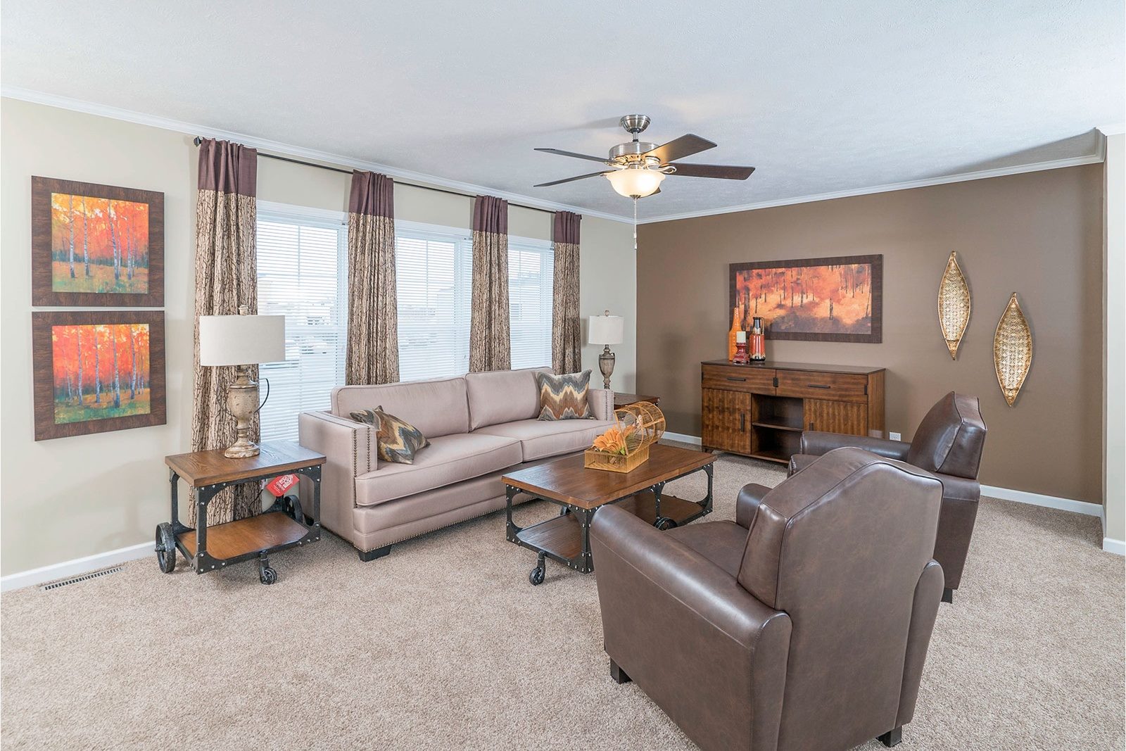 Modern living room with neutral tones, featuring a beige sofa, two brown armchairs, and a wooden coffee table. Autumn-themed art and decor enhance the cozy atmosphere.