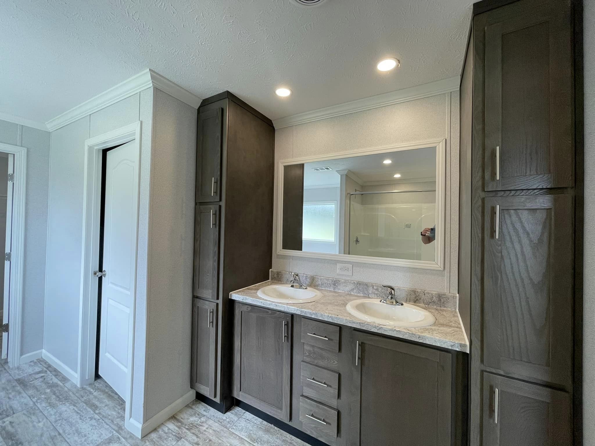 Modern bathroom with dual sinks set in a marble countertop, large mirror, and dark wood cabinets. Soft lighting adds a serene and clean ambiance.