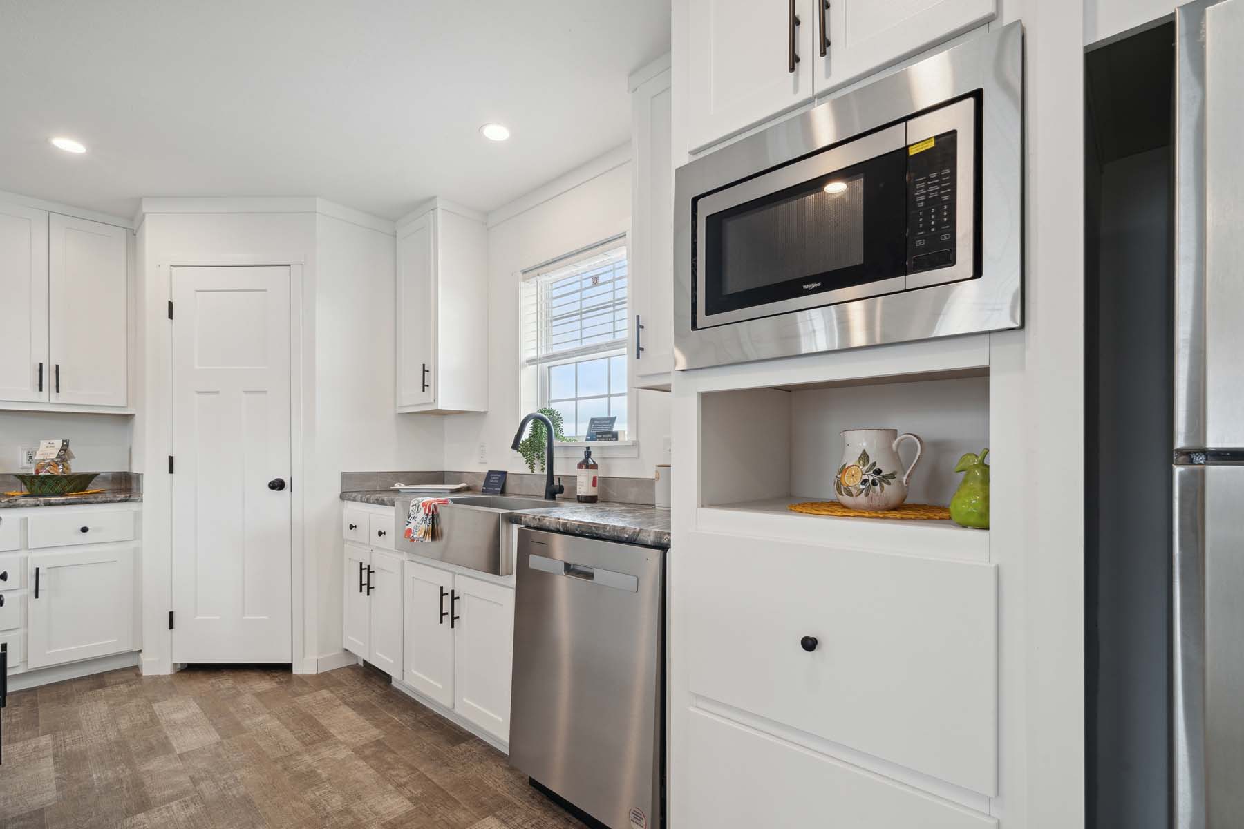 Modern kitchen with white cabinetry, stainless steel appliances, and wood flooring. A window above the sink provides natural light. Clean and inviting atmosphere.