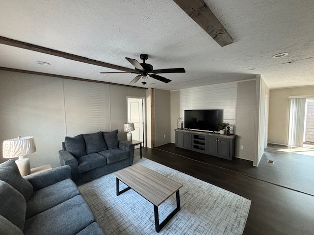 A modern living room with gray sofas, a coffee table, a TV atop a dark console, and a ceiling fan. Light streams in from patio doors, creating a cozy ambiance.