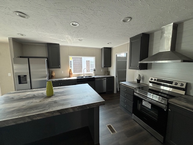 Modern kitchen with dark gray cabinets, stainless steel appliances, and a large island with a green vase. Bright lighting and sleek design.