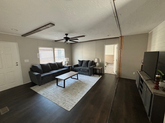 Spacious living room with dark wood flooring, two gray sofas, a large rug, and a TV console. Natural light streams through the window. Clean and modern.