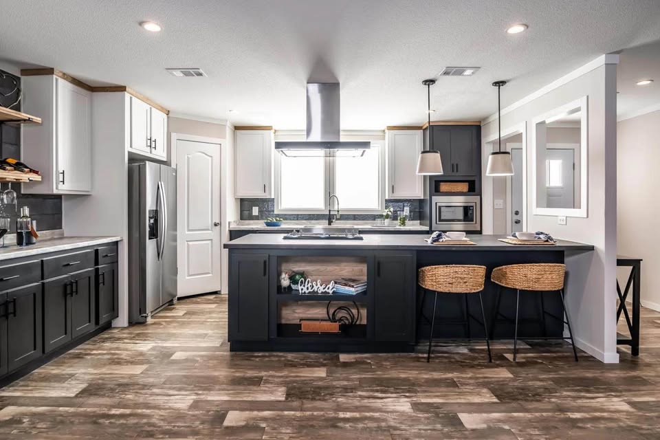 Modern kitchen with dark and white cabinets, stainless steel appliances, and a central island featuring wicker stools. Warm, inviting, and spacious.