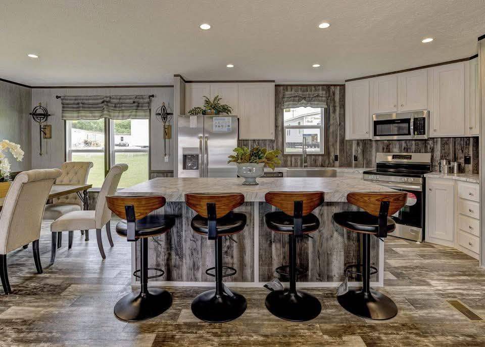 Spacious kitchen with a modern farmhouse style. Features a large island with four wooden barstools, stainless steel appliances, and rustic wood accents.