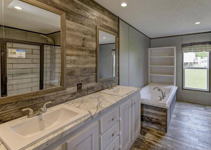 Modern bathroom with wood-paneled walls, a dual marble sink vanity, large mirrors, a built-in bathtub, open shelving, and natural light from a window.
