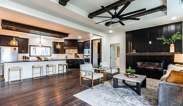 Modern open-concept living room and kitchen with dark wood flooring and cabinetry. Neutral furniture, fireplace, and ceiling fan create a cozy atmosphere.