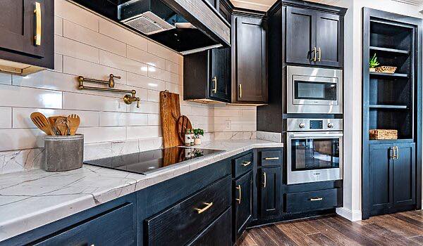 Modern kitchen with dark cabinets, white subway tile backsplash, and marble countertops. Built-in oven, stovetop, and open shelving add elegance.