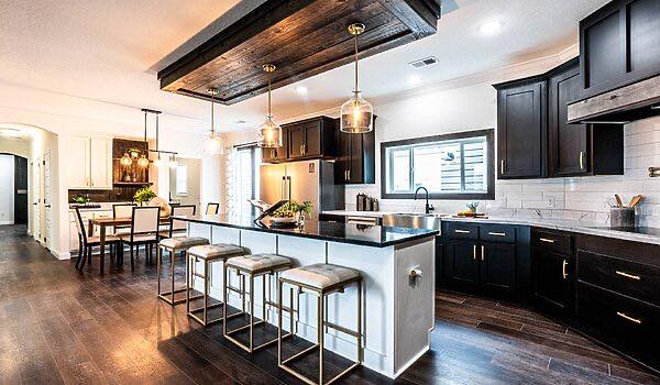 Spacious modern kitchen with dark wood cabinets, a large island with barstools, pendant lights, and a dining area. Warm, inviting atmosphere.