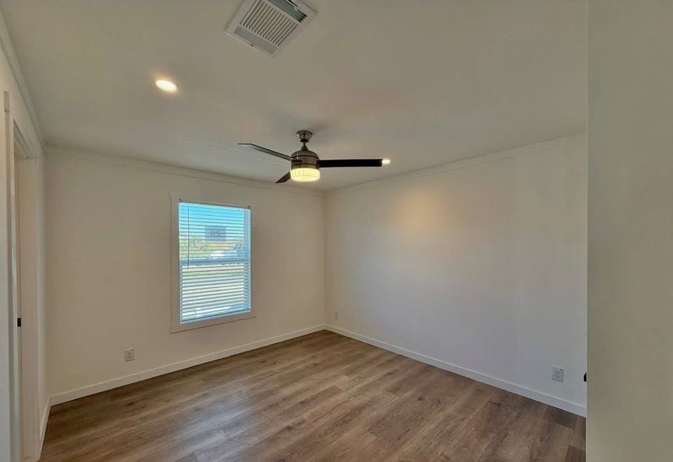 A minimalist room with white walls, wooden floor, ceiling fan, and a window with blinds. Bright, airy ambiance. No furniture, simple and modern.