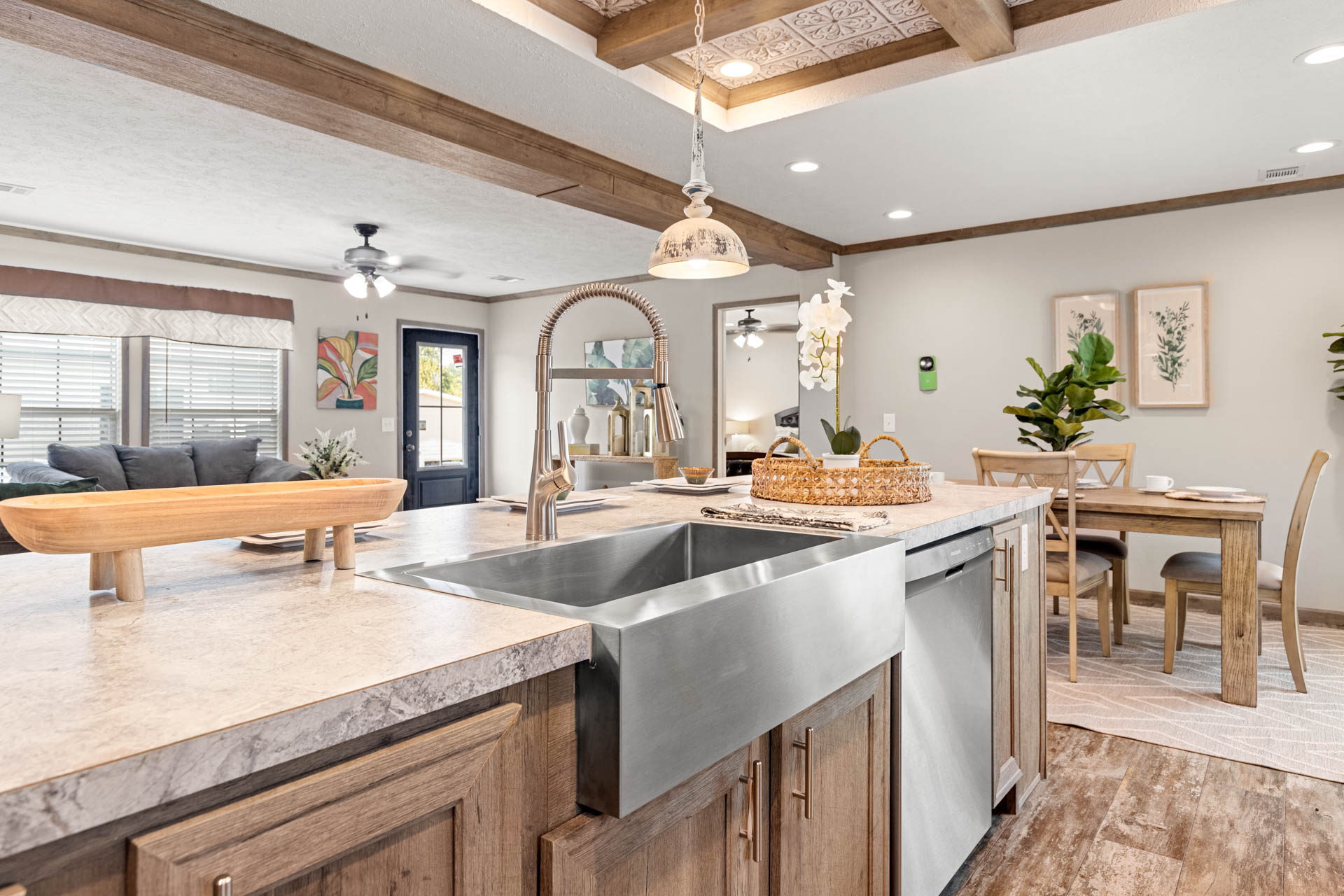 Open-concept kitchen and dining area with rustic wood beams, a large farmhouse sink, a wooden dining set, and cozy decor, creating a warm ambiance.