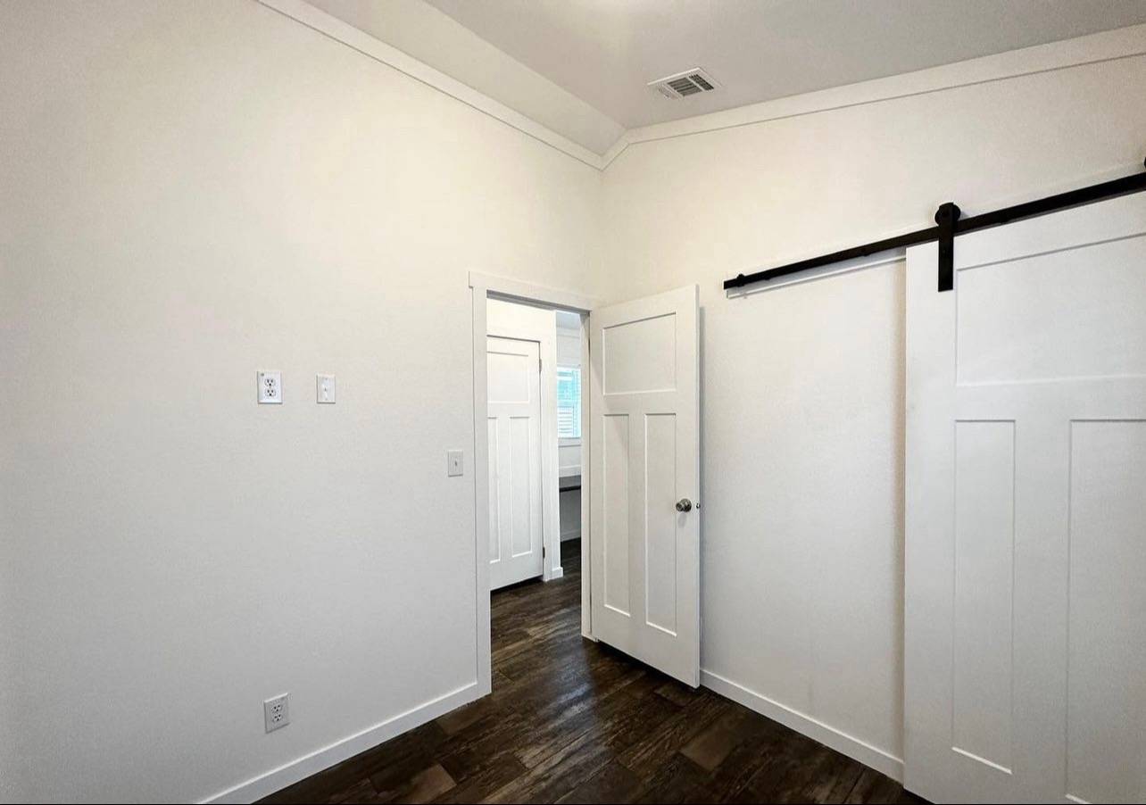 Bright room with white walls, dark wood floor, and two panel doors, one open and one sliding. Modern and minimalistic design.