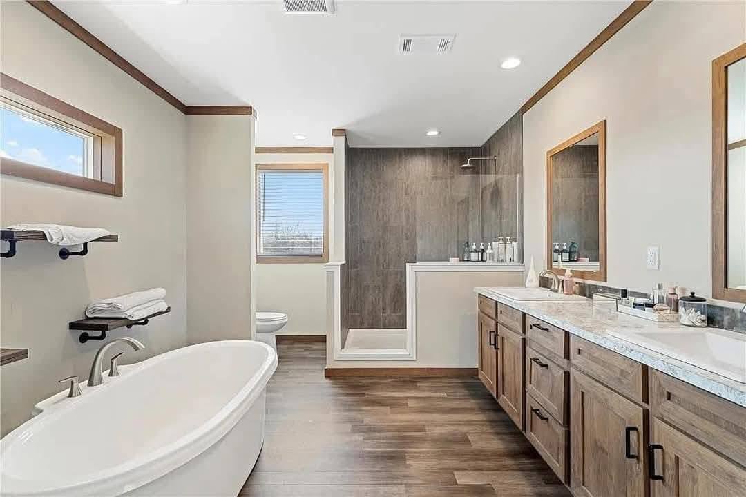 Modern bathroom with a freestanding bathtub, double vanity with wooden cabinets, and a walk-in shower with glass tiles. Bright and elegantly minimalist.