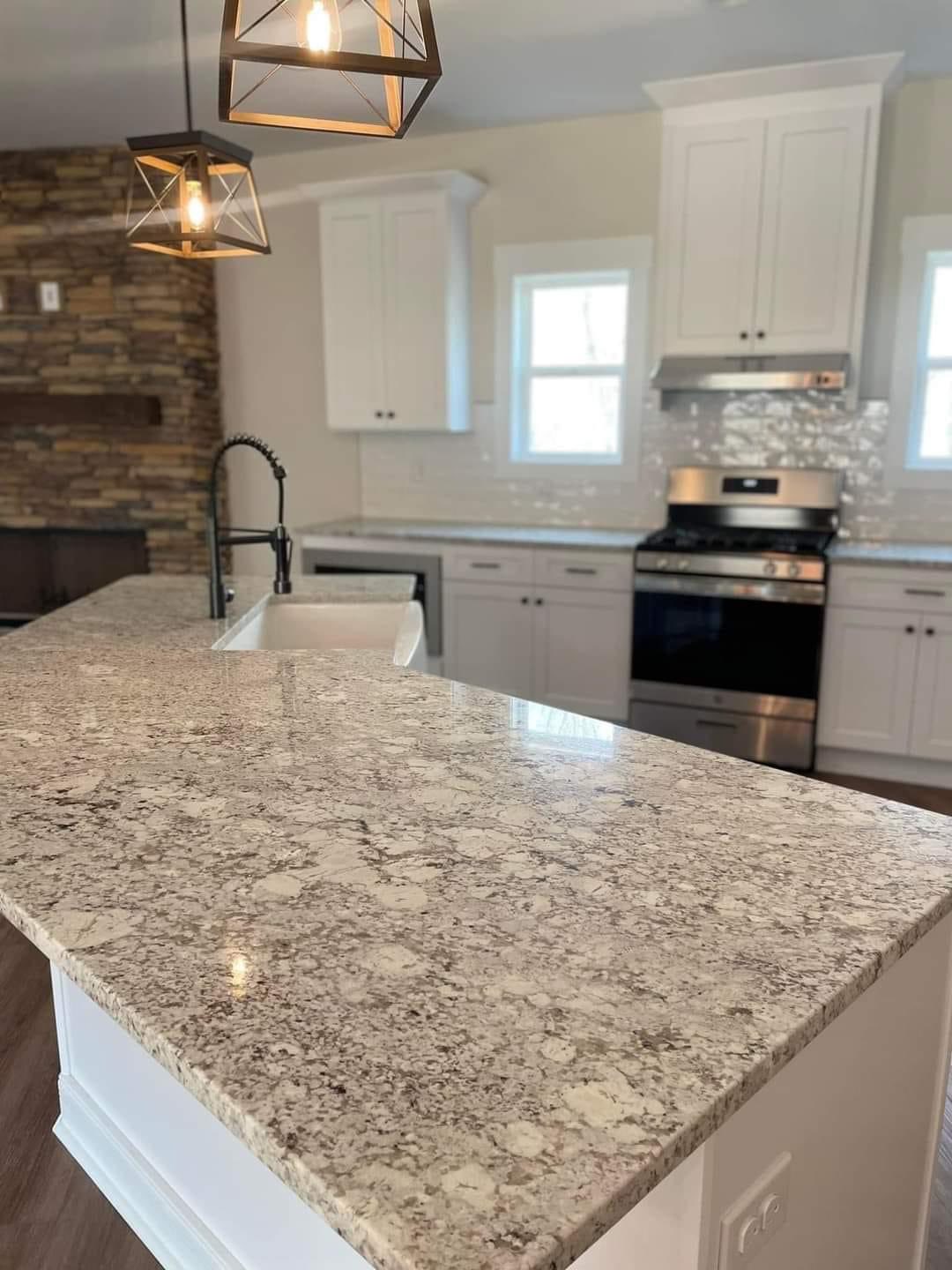 Elegant kitchen with granite countertops, white cabinets, and stainless steel stove. Pendant lights hang above, creating a warm and inviting atmosphere.
