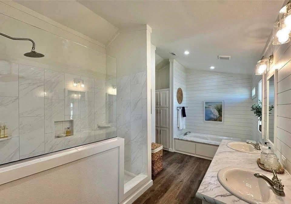 Modern bathroom with marble countertops, dual sinks, and warm lighting. Features a spacious shower and a separate bathtub with a calming, neutral palette.