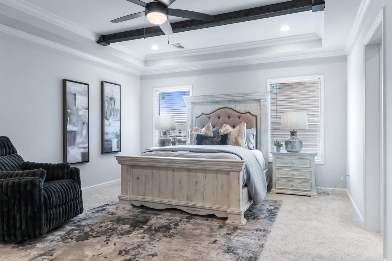 Serene bedroom with a rustic wooden bed, gray tufted headboard, soft linens, and two bedside lamps. Cozy armchair, abstract wall art, neutral tones.