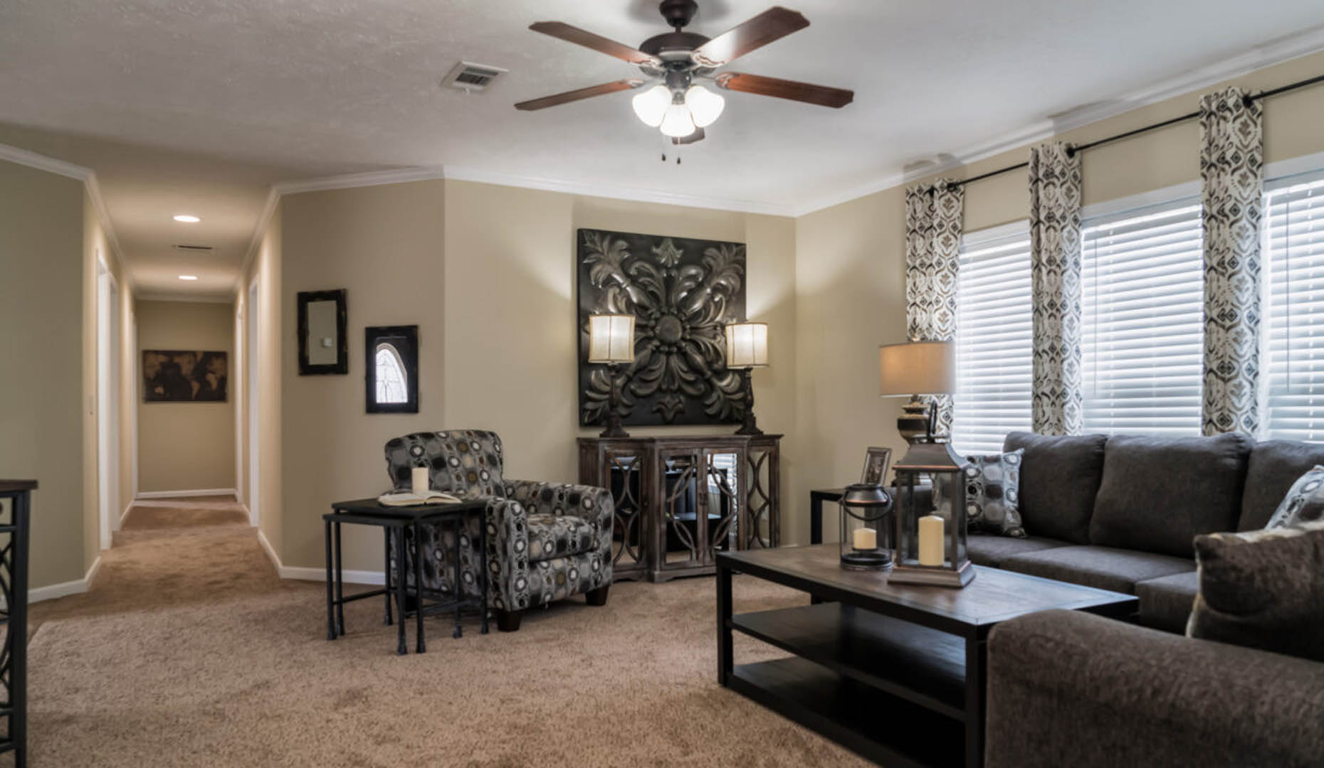 A cozy living room with patterned armchairs, a dark sofa, and decorative lamps. Soft lighting and earthy tones convey a warm, inviting atmosphere.