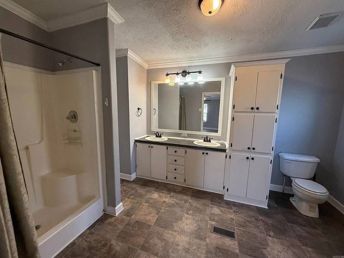 Spacious bathroom with gray walls, featuring a double-sink vanity with a large mirror, a white cabinet, a toilet, and a shower. The atmosphere is clean and modern.