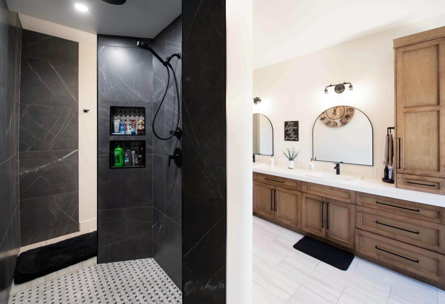 Modern bathroom with a black-tiled shower, shelves holding toiletries, and a rainfall showerhead. Adjacent is a double vanity with wooden cabinets, round mirrors, and ambient lighting, creating a sleek, elegant atmosphere.