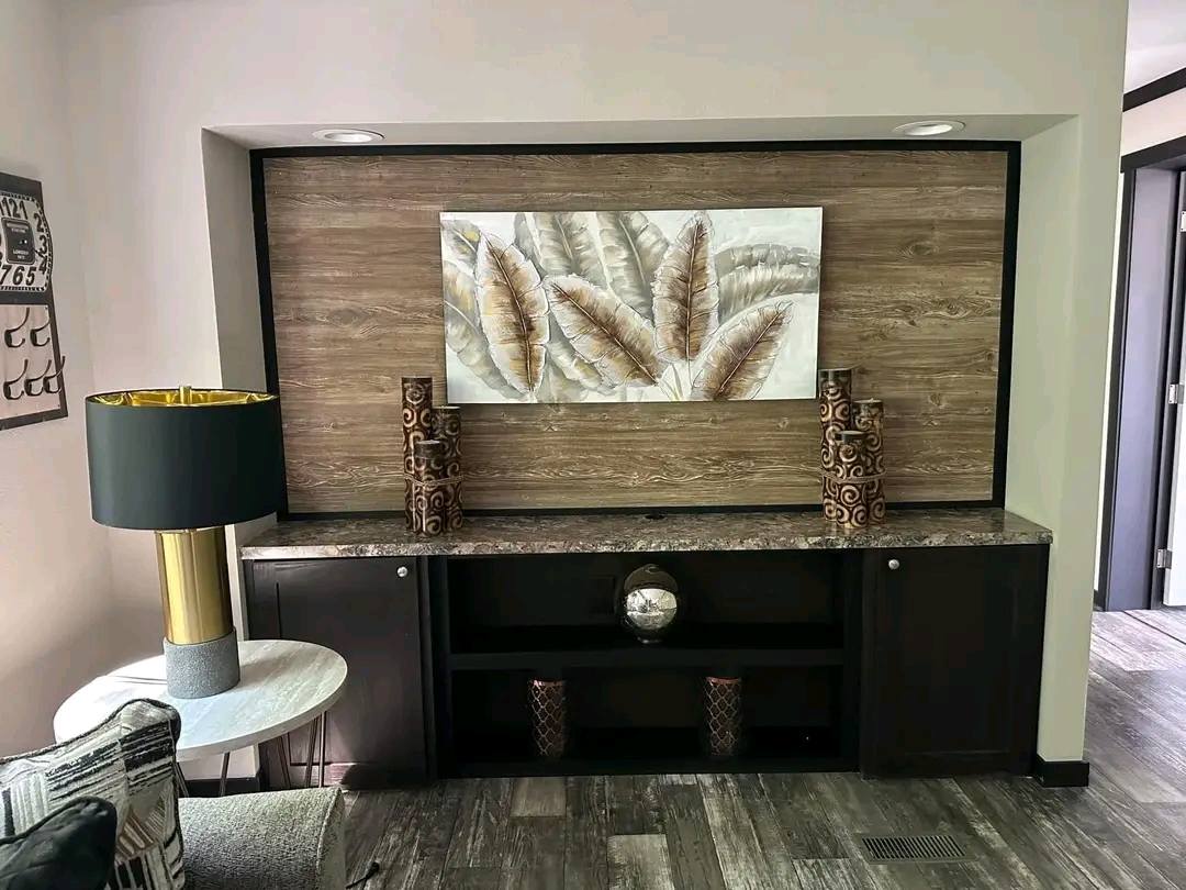 Decorative room corner with a wooden accent wall, featuring a feather painting. Two ornate vases and a reflective sphere adorn a dark console.