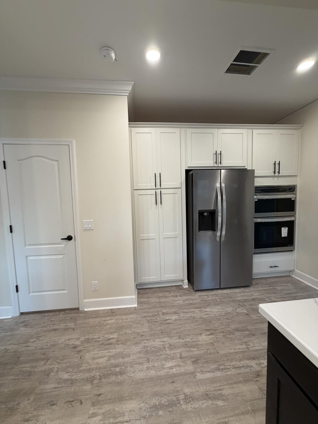 Modern kitchen interior with light wood flooring, white cabinets, and stainless steel appliances. Bright, clean, and minimalistic ambiance.