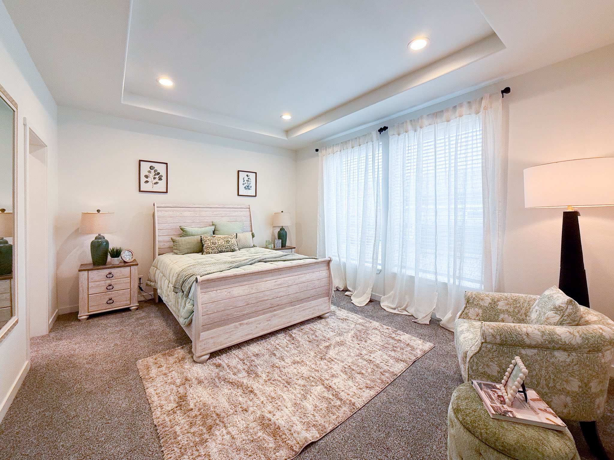 Spacious living room with a large gray sectional sofa, geometric wood coffee table, and modern decor. Soft lighting and neutral tones create a cozy feel.