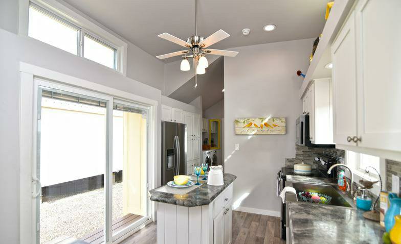 Bright kitchen featuring white cabinets, a marble island with dishes, stainless steel appliances, and sliding glass doors, conveying a modern, airy feel.