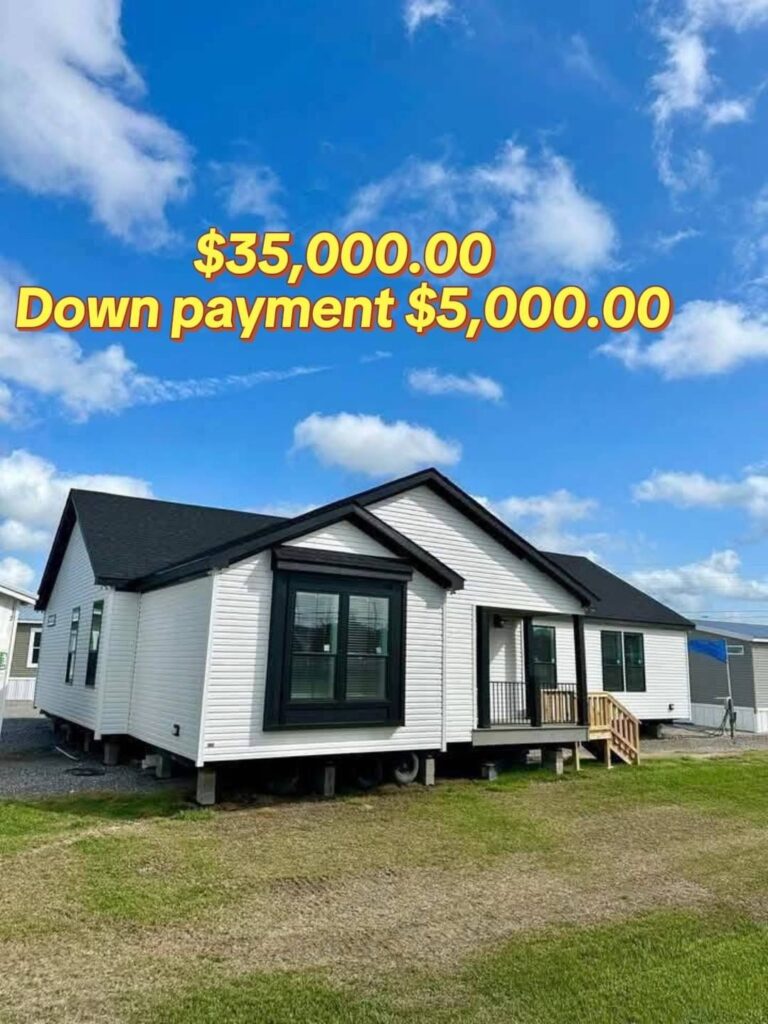Single-story white modular home with black trim under a vibrant blue sky with clouds. Text reads: "$35,000.00 Down payment $5,000.00".