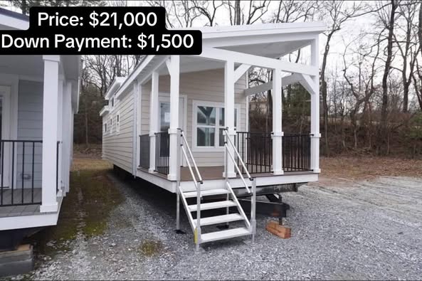 A beige tiny house with a covered porch and steps sits on gravel. A nearby structure is on the left. Text overlays indicate price and down payment.