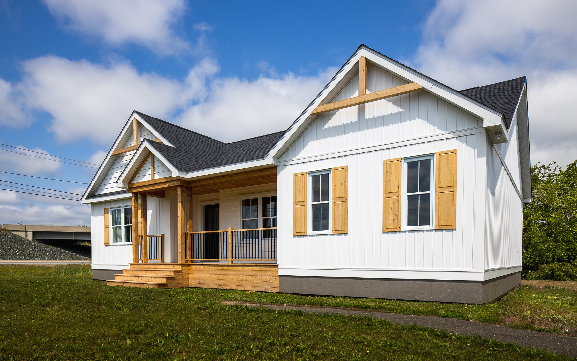 A charming white single-story house with wooden shutters and a gabled roof, set on a green lawn under a clear blue sky. Rustic and inviting ambiance.
