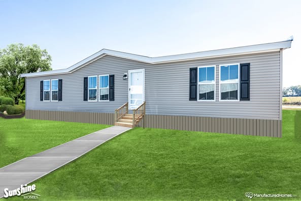 A light gray manufactured home with white trim and blue shutters sits on a grassy lawn. A paved walkway leads to the small wooden porch and front door.