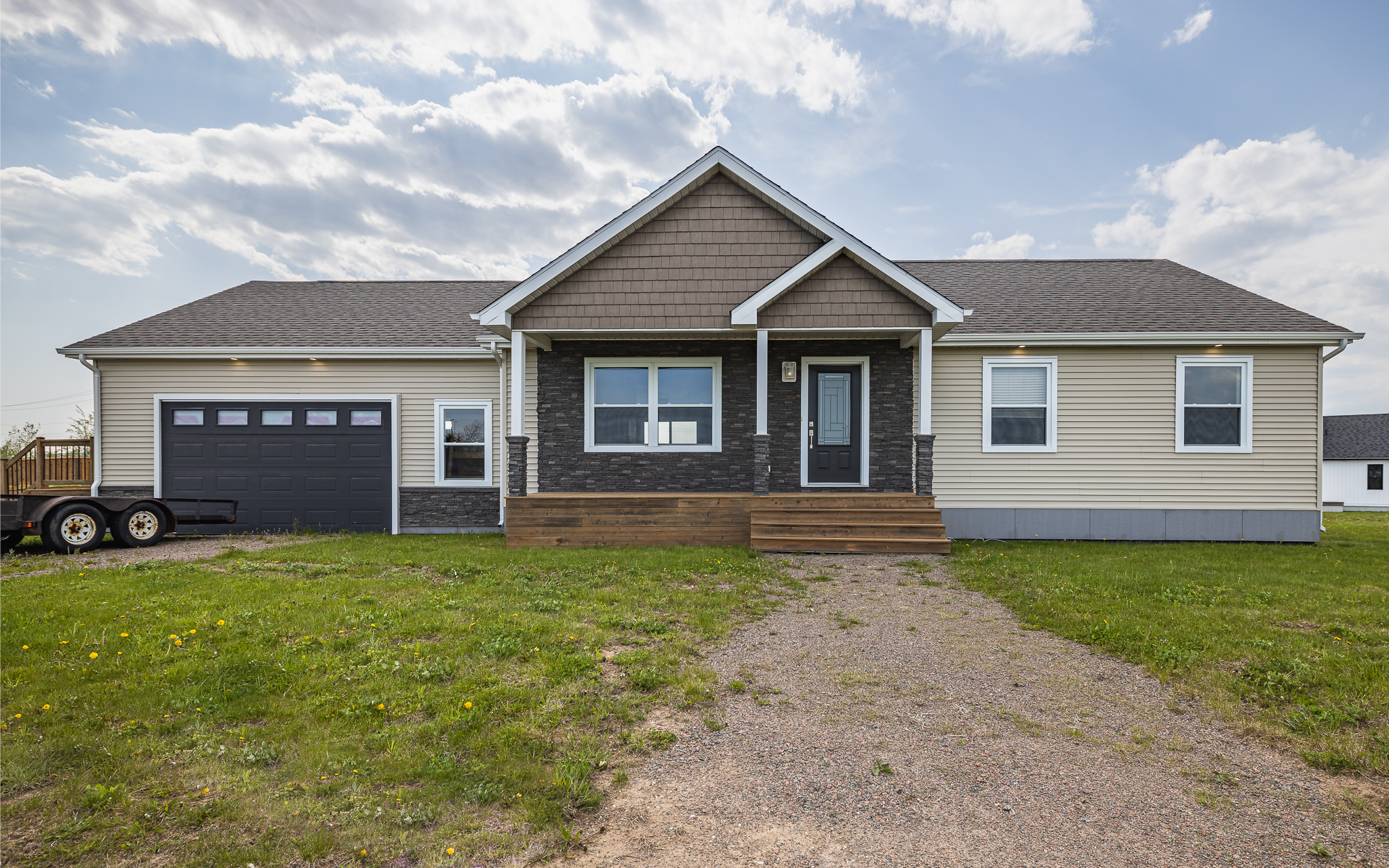 Single-story house with beige siding and dark brown accents. Attached garage on the left. Overcast sky, grassy yard. Calm and welcoming atmosphere.